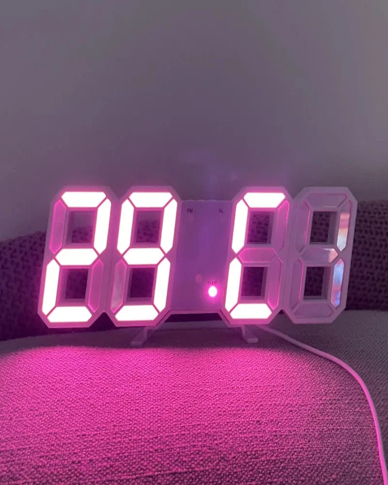Digital clock with pink LED display on a textured surface